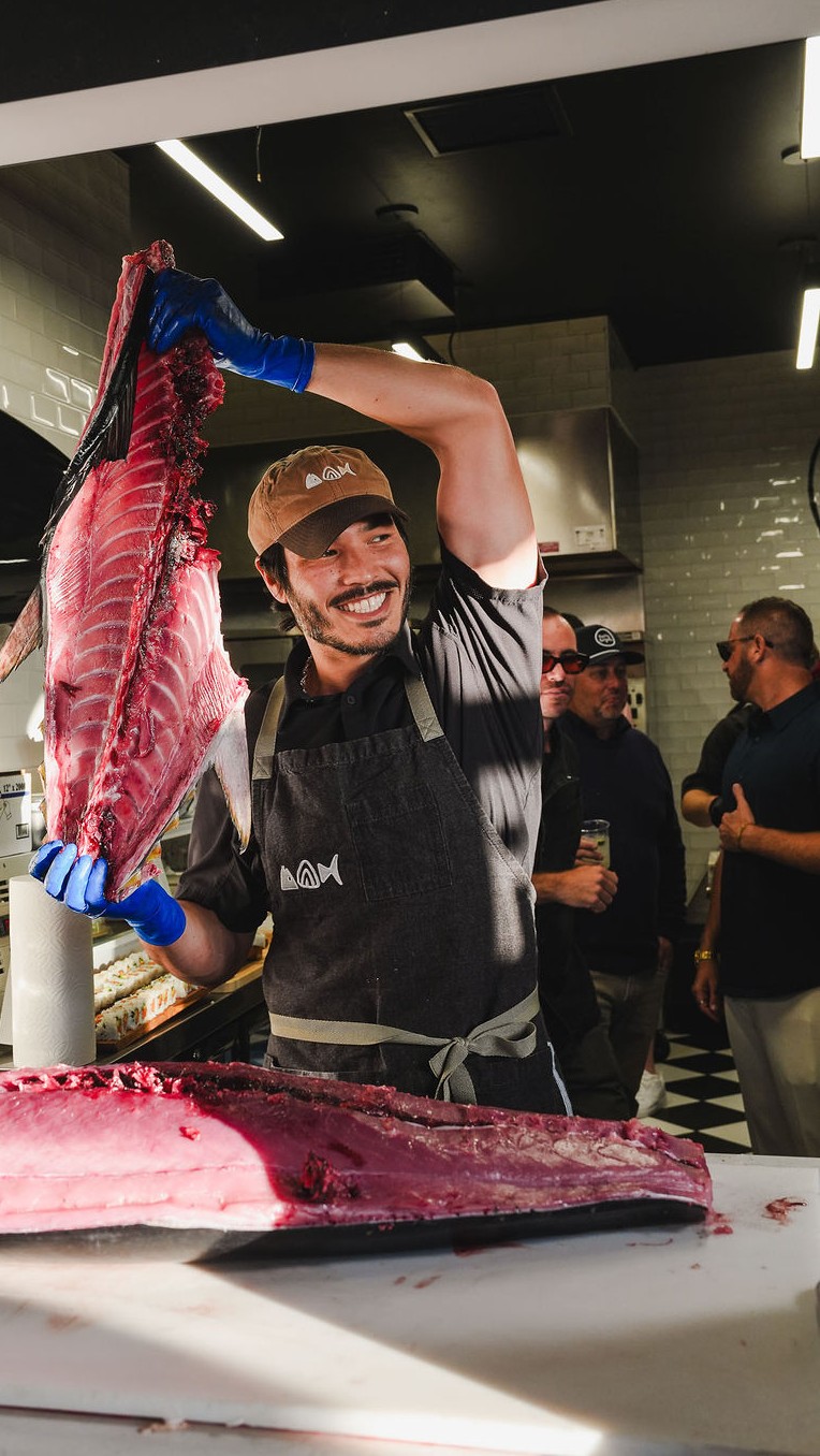 Blake Ito lifting a bluefin frame above the board, the loin already open in front of him.
