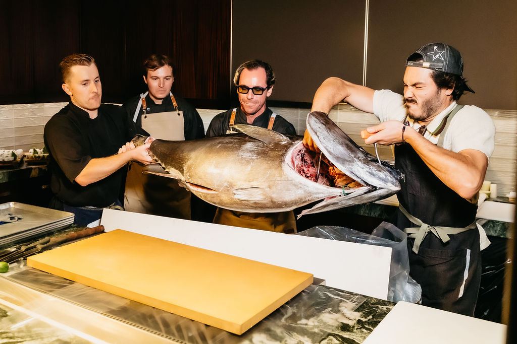 The team lifting a whole bluefin onto the board.