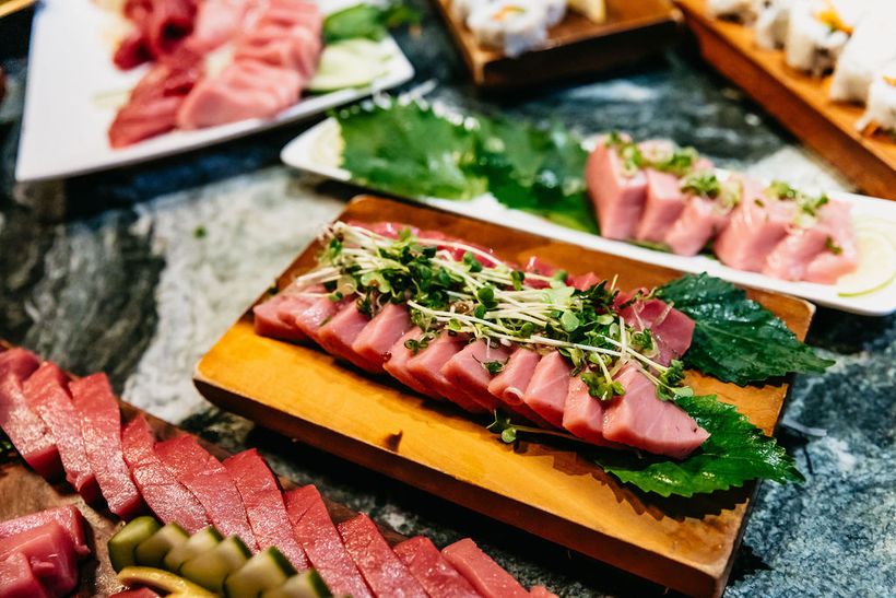 A board of bluefin cut and laid out on stone.