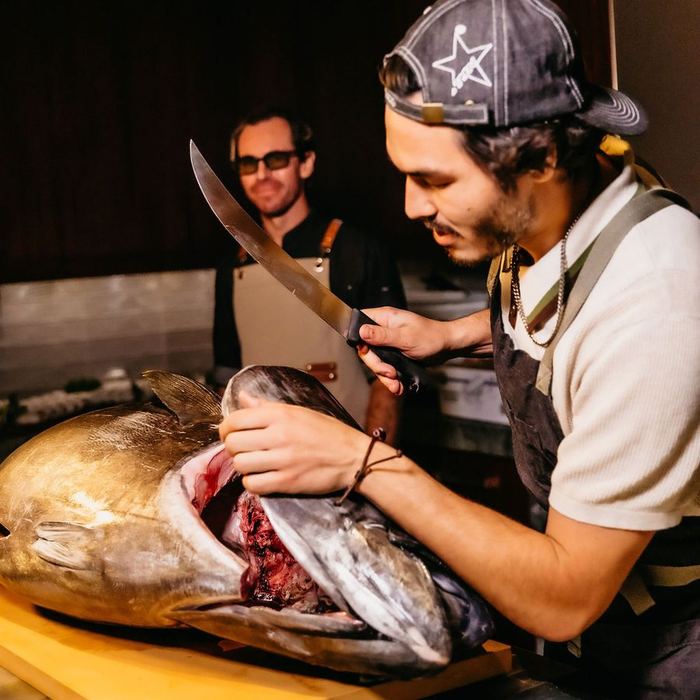 An itamae raising the knife over an opened bluefin.