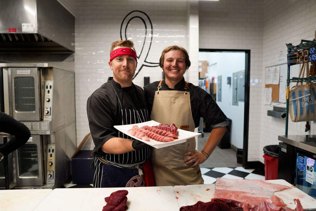 Two of the team holding a plate of toro.
